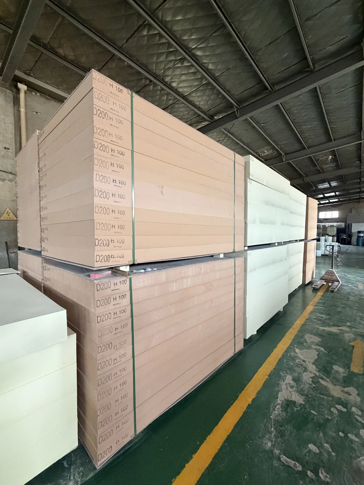 Board materials stacked on pallets along a warehouse aisle